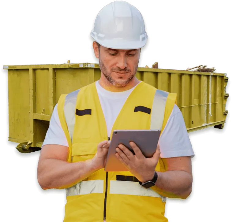 immagine di un operatore con elmento di sicurezza che guarda un tablet, sullo sfondo un cassone giallo per lo smaltimento dei rifiuti